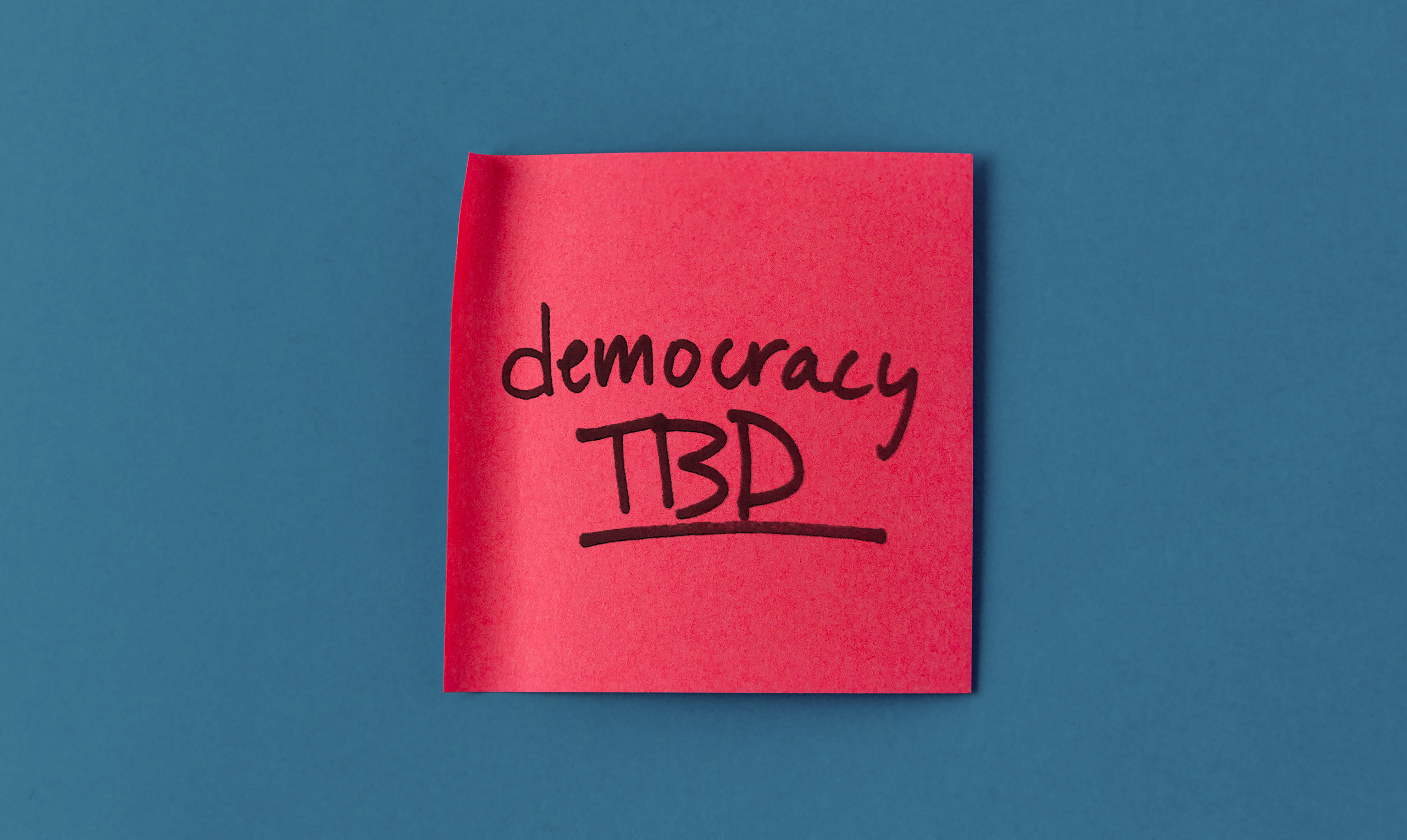 A red post-it note showing the title of the project, "Democracy TBD"